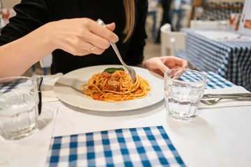 Close-up spaghetti Bolognese wind it around a fork. Parmesan cheese. Young woman eats Italian pasta...