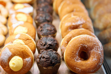 Donuts and rings. Hot pastries lie on the shelf in the cafe. Buns and chocolate muffins in the store.
