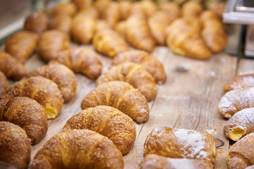 many of croissants. Hot pastries lie on the showcase in the cafe. Buns and bagels in the store.