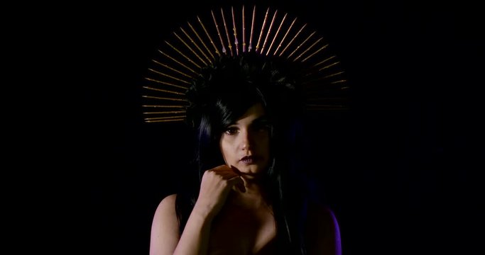 young woman with black spiked halo gothic headdress is standing in dark background