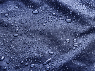Waterproof blue fabric with raindrops. Blue background.