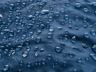 Waterproof blue fabric with raindrops. Blue background.