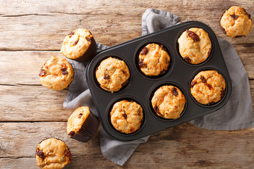 Homemade fresh muffins with sun-dried tomatoes and cheese close-up in a baking dish on the table....