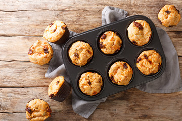 Homemade fresh muffins with sun-dried tomatoes and cheese close-up in a baking dish on the table. Horizontal top view