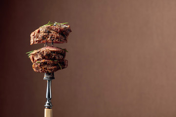 Grilled ribeye beef steak with rosemary on a brown background.
