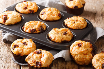 Freshly baked muffins with sun-dried tomatoes and cheddar cheese close-up in a baking dish. horizontal