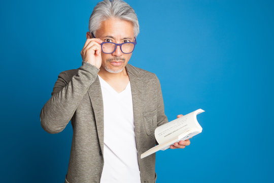 Hombre de origen as&aacute;tico, japon&eacute;s, leyendo un libro, hombre con lentes para poder leer