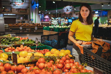 woman choosing vegetables from store shelf grocery shopping