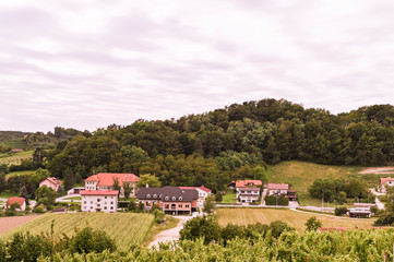 Fototapeta na wymiar Green hills and an old village in Slovenia. Traveling in Europe and tourism. Nature, sky and vineyards.