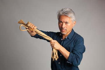 Hombre de mediana edad de origen japonés con una cuerda en sus manos y mirada amenazadora y muy...