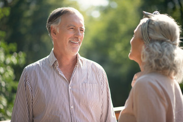 Grey-haired bearded man laughing while talking to wife