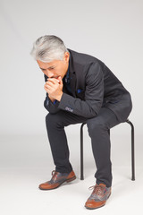Hombre de mediana edad, de origen japonés, sentado en una silla, reflexionando, pensando,...