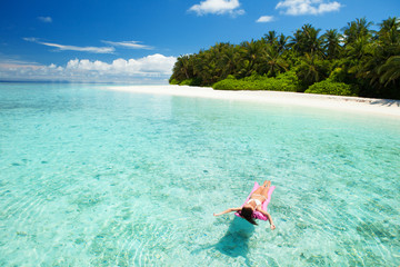 Woman swim and relax in the sea. Happy island lifestyle. White sand, crystal-blue sea of tropical...