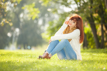 Obraz premium Young woman walking in the park. Beauty nature scene with colorful background at autumn season. Outdoor lifestyle. Happy smiling woman relax at fall