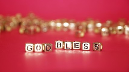 Gold beads with words 'TAX' on the pink background.