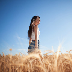 Happy woman enjoy the life in the field. Nature beauty, blue sky,white clouds and field with golden wheat. Outdoor lifestyle. Freedom concept. Woman walk in summer field