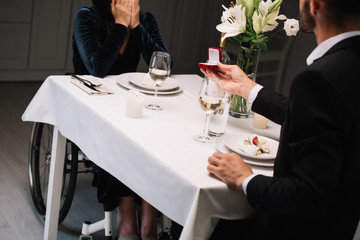 cropped view of man making wedding proposal to disabled girlfriend during romantic dinner