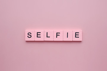 Selfie word wooden cubes on a pink background