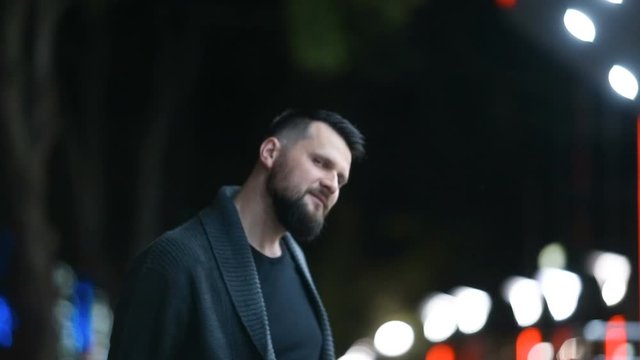Close-up of a handsome bearded man raising his hand in farewell, saying goodbye  and leaving on the evening street