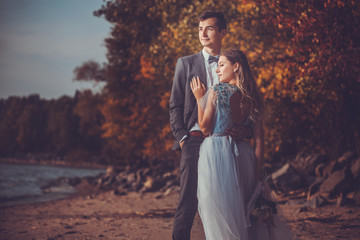 happy bride and groom are walking on the autumn beach