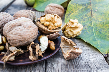 Walnuts and walnut kernels lie on a bowl on a rustic old wooden table. Walnut kernels.