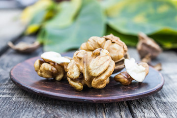 Walnuts and walnut kernels lie on a bowl on a rustic old wooden table. Walnut kernels.