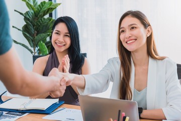 Beautiful young Asian girl and businesswoman meeting & shake hands at a office space with a laptop...
