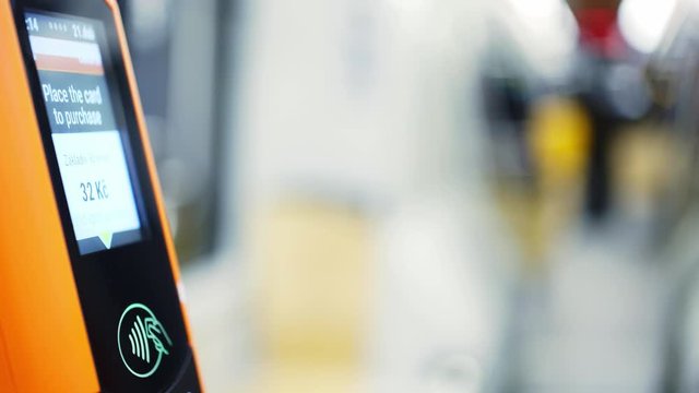 Faceless passenger payment via electronic device in public transport. Detail view female hand with smartwatch on wrist touching modern tram validator for contactless payments at blurred background