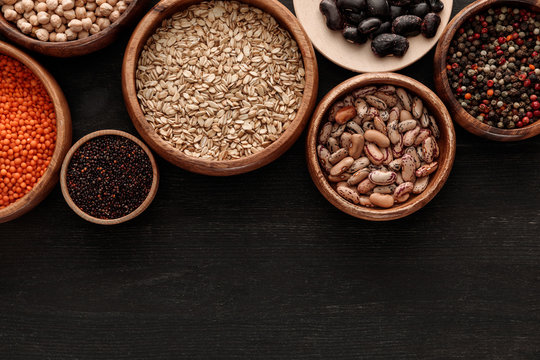 top view of raw beans, cereals and spice in bowls on dark wooden surface with copy space © LIGHTFIELD STUDIOS