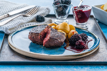 Pan-fried venison with blackberry sauce and boiled baby potatoes