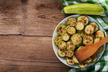 Fried zucchini slices with parsley on a white plate close up