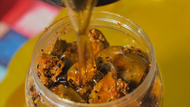Shot of adding mustard oil into a jar full of fresh mango pickle / achar. 