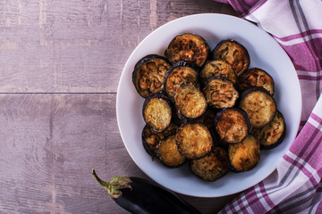 fried eggplant on the plate on rustic wooden background - top view. copyspase