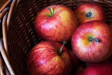 Red apples in basket on grey wooden background