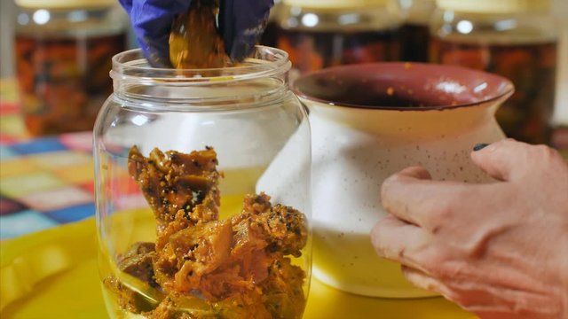 A women transferring mango pickle / achar to a glass jar. 