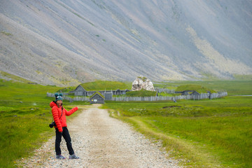 Picture of asian woman travel of traditional viking village. wooden houses near the mountain first settlements in Iceland