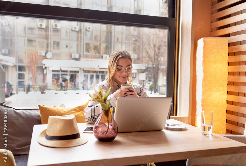 Wall mural portrait of young woman using laptop at cafe, she is working on laptop computer at a coffee shop.