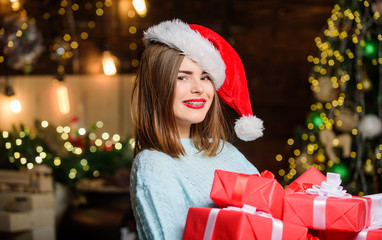 Obraz na płótnie Canvas Lady santa celebrate christmas at home. Cozy christmas atmosphere. Woman santa claus hat on christmas eve. Girl stylish makeup red lips hold many christmas gifts. Bring magic into someone elses life