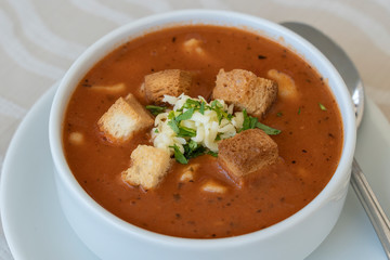 Tomato soup with croutons, cheese and fresh parsley, closeup