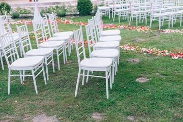 wedding or ceremony set up in garden, white chairs