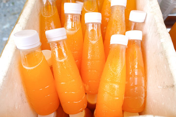 Bottles of fresh fruit juice, in a wooden barrel with ice.