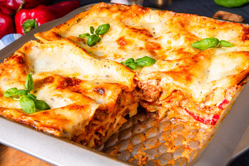 rustic spicy lasagne with basil on the tin.