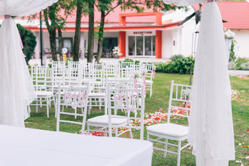 wedding or ceremony set up in garden, white chairs