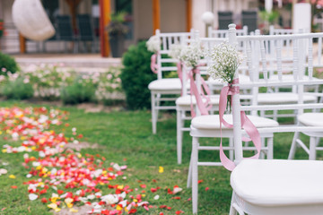 wedding or ceremony set up in garden, white chairs