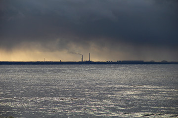 Industrial plant on seashore and smoke in dark sky