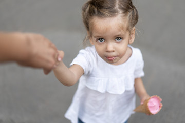 Little caucasian girl 3 years old eats ice cream closeup portrait