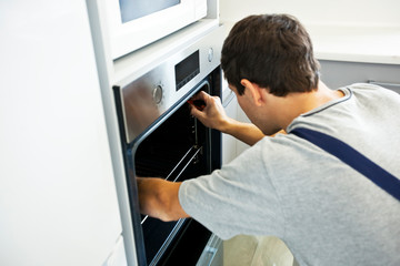 The repairer is fixing the electric oven