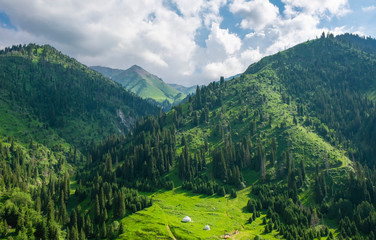 Beautiful view to the high green mountains and white kazakh national yurts, Almaty, Kazakhstan