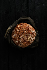 Freshly baked bread on black wooden background. Top view. Copy space.