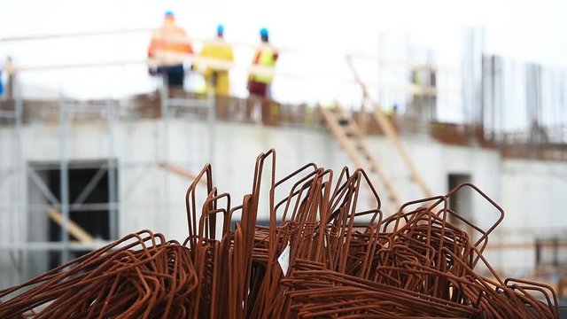 Detail with reinforcing iron bars on a construction site. Construction workers on the background.
